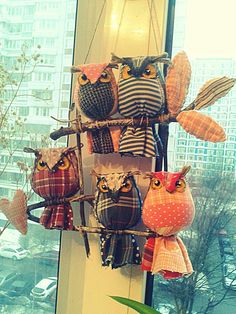 several stuffed owls are hanging on a window sill in front of a cityscape