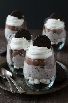 three desserts with oreo cookies and whipped cream in glass dishes on a wooden table