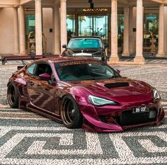 a purple sports car parked in front of a large building with columns on it's sides