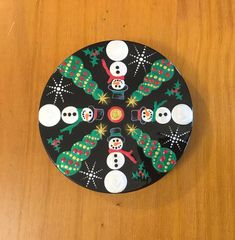 a wooden table topped with a black plate covered in snowmen