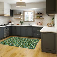 a kitchen with wooden floors and gray cabinets, white counter tops and green mats on the floor