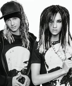 two people with dreadlocks standing next to each other in front of a white background