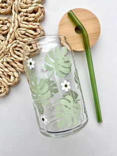 a glass vase sitting on top of a table next to a green straw and a wooden spoon