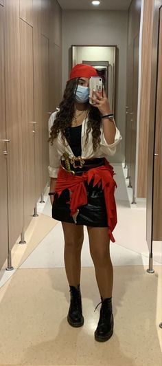 a woman wearing a pirate costume taking a selfie in a hallway with her cell phone