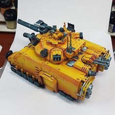 a yellow toy tank sitting on top of a table