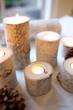 some candles are sitting on a table next to pine cones and other items that have been made out of wood