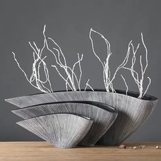 two vases with branches in them sitting on a table