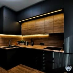 a modern kitchen with black cabinets and wood flooring is lit by recessed lighting