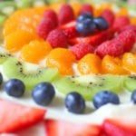 the fruit pizza is decorated with fresh berries and kiwis