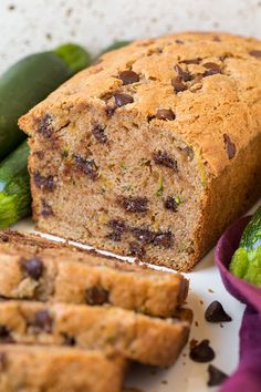 a loaf of chocolate chip zucchini bread on a plate next to cucumbers