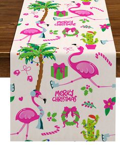 a table cloth with pink flamingos and palm trees on it, along with merry christmas