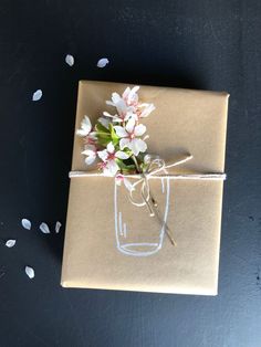 a package with flowers tied to it sitting on top of a black table next to confetti