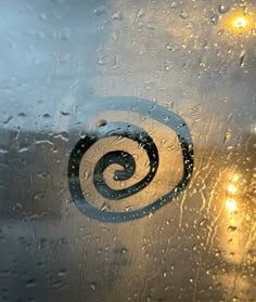 a close up of a window with raindrops and street lights in the background