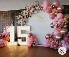 balloons are arranged around the number fifteen sign and flowers in front of it, along with other decorations