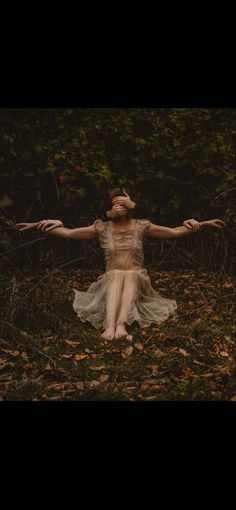 a woman is sitting in the grass with her arms spread out and hands stretched out