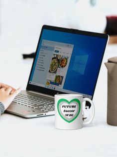 a person sitting at a table with a laptop and coffee mug in front of them