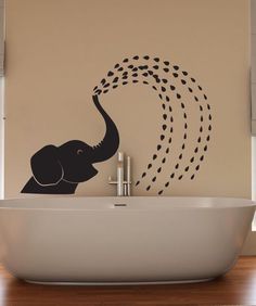 an elephant with its trunk in the air above a bathtub and wall sticker