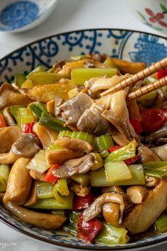 a bowl filled with stir fry vegetables and chopsticks on top of a table