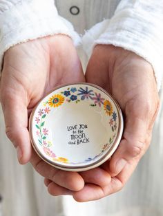 a person holding a small bowl that says love you to the moon and back on it