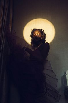 a woman standing in front of a window with the sun shining down on her face