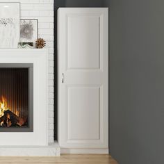 a fire place in a living room next to a white door and wall with pictures on it