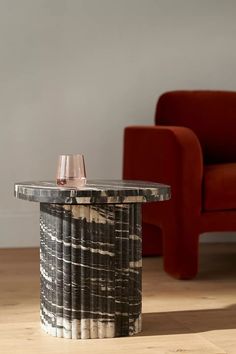 a wine glass sitting on top of a table next to a red chair in a living room