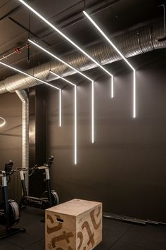 an empty gym with exercise equipment and lights hanging from the ceiling in front of it