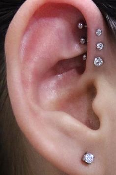 a woman's ear with three different piercings