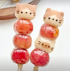 some kind of candy that looks like cats sitting on top of each other with apples in front of them