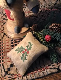 a teddy bear sitting on top of a wooden table next to a pillow and pine cones