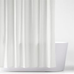 a white shower curtain sitting on top of a bath tub