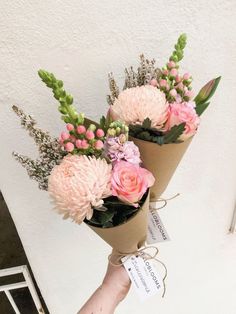 two pink flowers are wrapped in brown paper