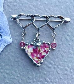 This lovely sterling silver triple-heart brooch with rings was made from pink chintz broken china and recycled into a heart charm that dangles from the brooch. The china charm was decorative soldered with a lead free silver solder. The china piece measures 3/4 inches wide and 3/4 inch long. The china charm dangles from a sterling silver twisted jump ring at the top of the china piece, There are also pink Swarovski crystals and sterling silver bead caps that are suspended from a sterling silver h Pink Heart-shaped Jewelry For Gift Making, Heart-shaped Brooch Jewelry Gift, Vintage Silver Brooches For Valentine's Day, Heart-shaped Valentine's Day Brooch Pin, Antique Heart-shaped Brooch For Gift, Antique Heart-shaped Brooches For Gifts, Broken China Jewelry, Pink Swarovski, China Jewelry