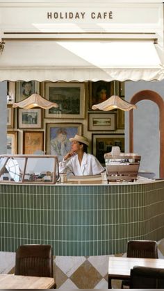 a man sitting at a counter in front of a restaurant with pictures on the wall