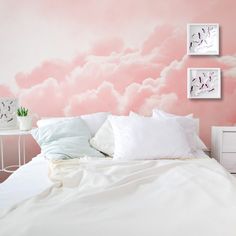 a bedroom with pink clouds painted on the wall and white bedding, along with two nightstands