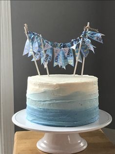 a cake with blue frosting and flags on top is sitting on a wooden table