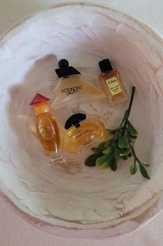 three bottles of perfume sitting in a bowl