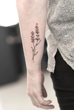 a woman's arm with a small flower tattoo on the left side of her wrist