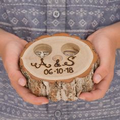 a person holding a piece of wood with two rings on it and the word love spelled in black