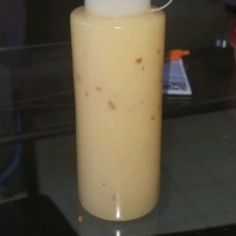 a yellow bottle with a white lid sitting on top of a glass table next to a black counter