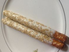 two hot dogs on a white plate with gold sprinkles