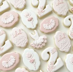 many decorated cookies are displayed on a white tablecloth with pink and white icing