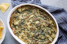 a casserole dish filled with spinach, cheese and tortilla chips