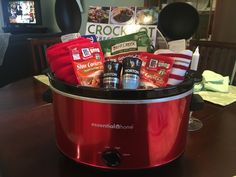 a red crock pot filled with food on top of a wooden table next to a tv