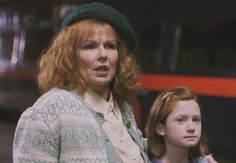 two women standing next to each other in front of a bus