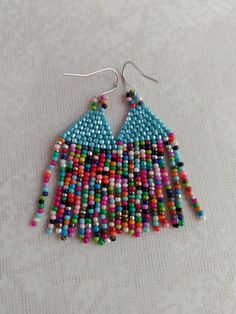 A colorful fringed earring created with three cut seed beads or cube seed beads combined with a round seed bead mix. A fantastic way to wear color.  Apple green or turquoise blue atop cake sprinkle. Sounds like summer fun to me. A great gift too! Unique Colorful Beaded Summer Earrings, Colorful Green Beaded Earrings For The Beach, Vibrant Colorful Beaded Earrings For Beach, Rainbow Seed Bead Earrings, Colorful Summer Jewelry, Multicolor Hand-strung Beaded Earrings, Woven Earrings, Blue Apple, Earrings Turquoise