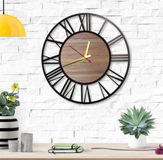 a large clock on the wall in a room with white brick walls and green plants