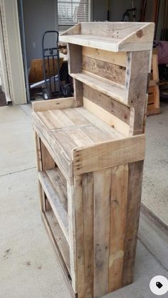 a wooden bench made out of pallets on the side of a building with an open door