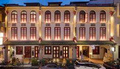 an old building with many windows and red shutters on the front is lit up at night