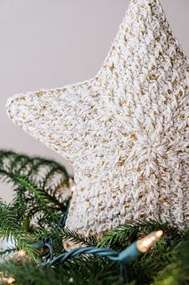 a crocheted star ornament sitting on top of a christmas tree